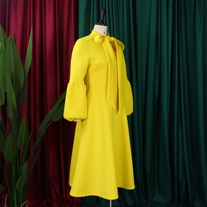 Detail of yellow long sleeve dress with puff sleeves and large bow neck tie design