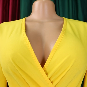 Detail view of a bright yellow dress with a deep V-neck and wrap style collar design