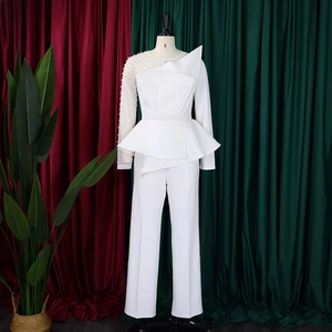 Detail of white mesh sleeve with pearl beads and peplum waist on an elegant jumpsuit