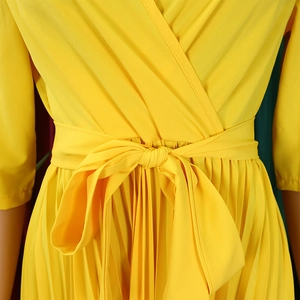 Detail of elegant yellow pleated dress featuring a self-tie waist belt and fabric texture