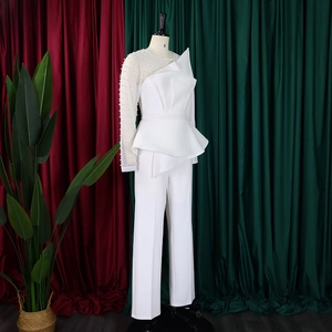 Detail of white jumpsuit with mesh sleeve and pearl beads on a mannequin display