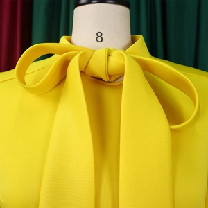 Detail of elegant yellow evening dress featuring a large bow neckline and puff sleeves