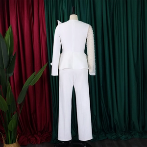 Detail of white jumpsuit featuring sheer mesh sleeve with delicate pearl embellishments