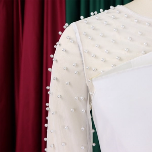 Detail of white mesh sleeves with delicate faux pearl embellishments on a jumpsuit
