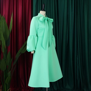 Detail of mint green dress with puff sleeves and oversized bow neckline on a mannequin