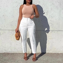 Detail of high-waist white pleated trousers with a sleek sleeveless top in a modern urban style