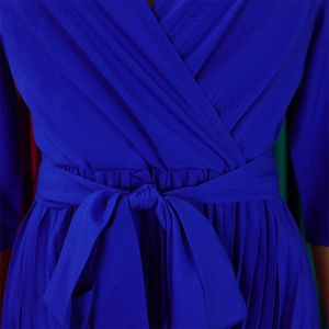 Detail of royal blue pleated dress featuring V-neck wrap design and bow tie waist belt