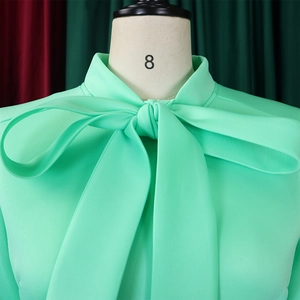 Detail of mint green plus size dress with an elegant oversized pussy-bow tie neckline