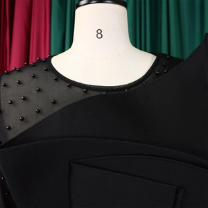 Detail of mesh patchwork and hand-sewn black beads on a sleek jumpsuit shoulder