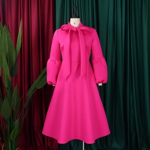 Detail of rose red dress featuring a tied bow neckline and elegant puff sleeves