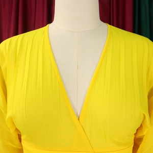 Close-up of bright yellow pleated V-neck chiffon top with detailed fabric texture