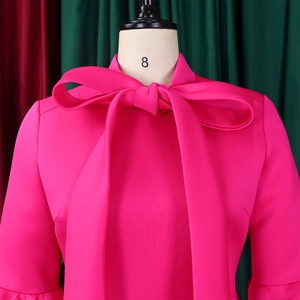 Detail of fuchsia cocktail dress featuring oversized bow neckline and ruffle cuffs