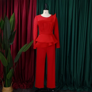 Detail of red peplum jumpsuit showing mesh sleeves and intricate beadwork on mannequin