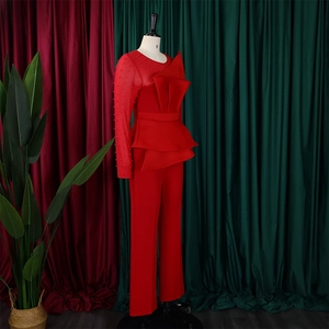 Detail of red jumpsuit featuring mesh sleeves, pearl embellishments and peplum waist design