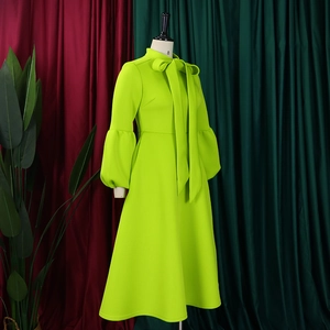 Detail of lime green dress featuring high neckline with elegant bow tie and lantern sleeves