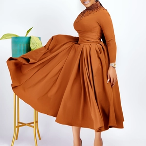 Detail of high neck beaded embroidery and flowy pleated skirt on a caramel maxi dress