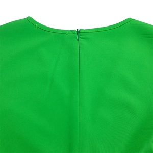 Detail of the bright green dress featuring a back invisible zipper and round neckline