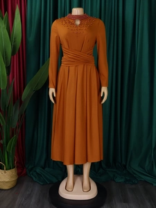 Detail of high neck orange dress with intricate beadwork and waist pleats