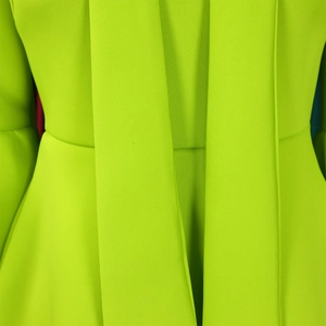 Detailed close-up of fluorescent neon green dress fabric featuring waist pleats and tie bow