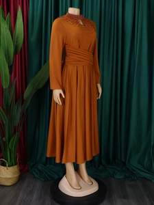 Detail of high neck orange maxi dress with decorative beadwork and pleated waist design
