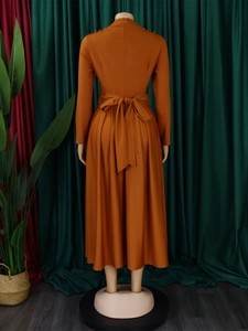 Detailed back view of a burnt orange maxi dress with shoulder beads and a waist tie bow