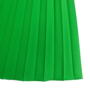 Detail of bright green pleated fabric with precise accordion folds and stitched hemline