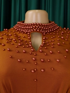 Detail of high neck orange dress with beadwork, teardrop cutout and knit texture