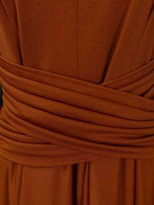 Detail of burnt orange ribbed dress featuring elegant crisscross pleated design and fine stitching