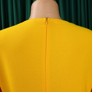 Detailed close-up of yellow pleated dress back with concealed zipper and fine fabric texture