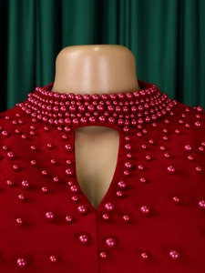 Detailed close-up of high neck red dress with elegant beads and keyhole cutout