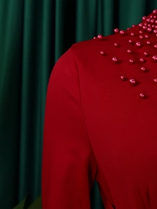 Close-up of elegant red beaded shoulder detail on a high-neck evening dress