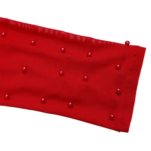 Detail of red mesh fabric with decorative pearls on an elegant jumpsuit sleeve