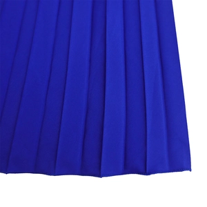 Detail of royal blue pleated fabric with satin finish and vertical folds on dress hem