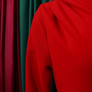 Macro detail of red pleated dress showing high neckline and textured fabric quality