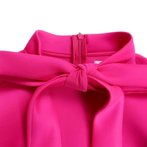 Close-up of mock neck dress detail with large bow tie and hidden zipper in magenta