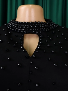 Detail of high neck black dress featuring beaded embellishments and keyhole neckline cutout