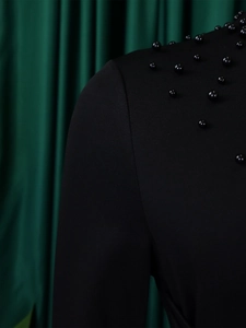 Detailed close-up of elegant black high neck dress featuring premium beadwork accents