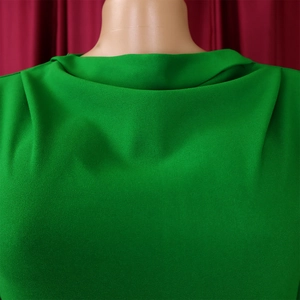 Detailed view of the elegant pleated green dress with high collar and textured fabric