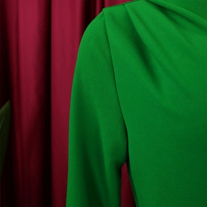 Detail of emerald green pleated sleeve on an elegant dress with textured fabric