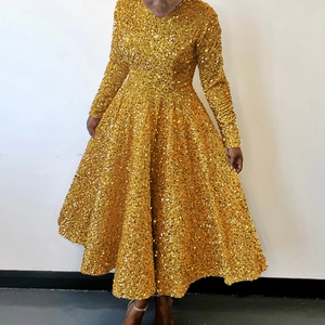 Detailed view of high-density gold sequins on long-sleeve evening gown with light reflection
