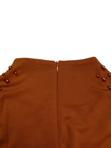 Detail of waist design featuring invisible zipper and pearl beads on brown dress
