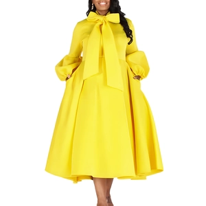 Detail of a bright yellow dress with puff sleeves and a large bow tie on the neckline