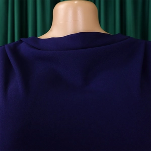 Detailed close-up of the round neckline and sewing texture on this navy blue pleated dress
