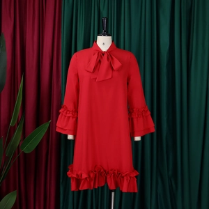 Detail of red chiffon dress featuring bow tie neckline and layered ruffle sleeves