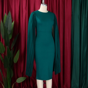 Detail of dark green dress showing pleated cape sleeves and elegant slim fit texture