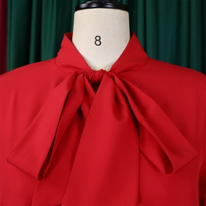 Detailed view of red tie-neck blouse with elegant pussy-bow and woven texture