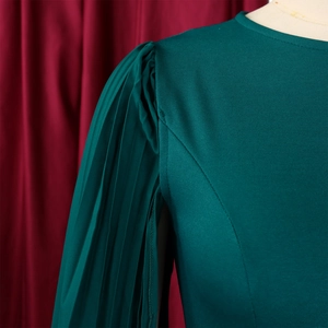 Macro detail of elegant dark green pleated shoulder design on a slim-fit dress fabric