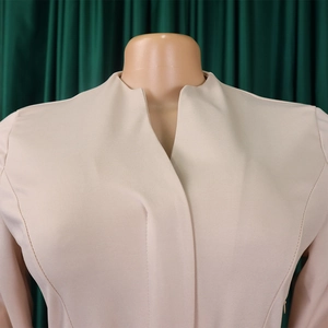 Détail de l'encolure en V et de la texture du tissu d'une robe africaine de couleur beige