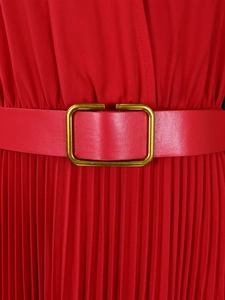 Detail of red pleated dress featuring a gold square buckle belt and fabric texture