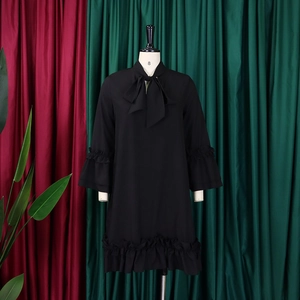 Detail of black A-line dress featuring a tie-neck bow and tiered ruffle sleeve cuffs